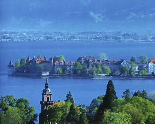 A lakeside town surrounded by blue water and green banks